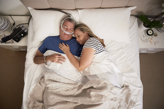 Man sleeping peacefully in bed with partner while wearing the AirFit P30i mask