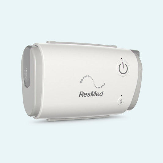 ResMed AirMini™ - AutoSet™ Travel Portable CPAP Machine on light blue background.